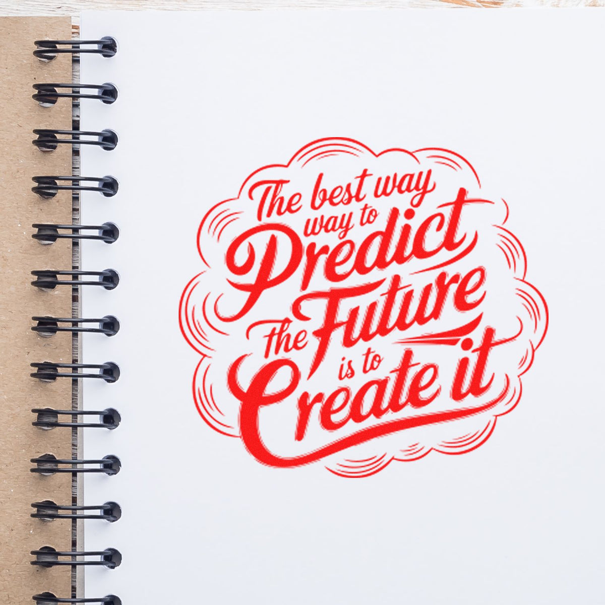 Red inspirational rubber stamp quote on a notebook page: The best way to predict the future is to create it.