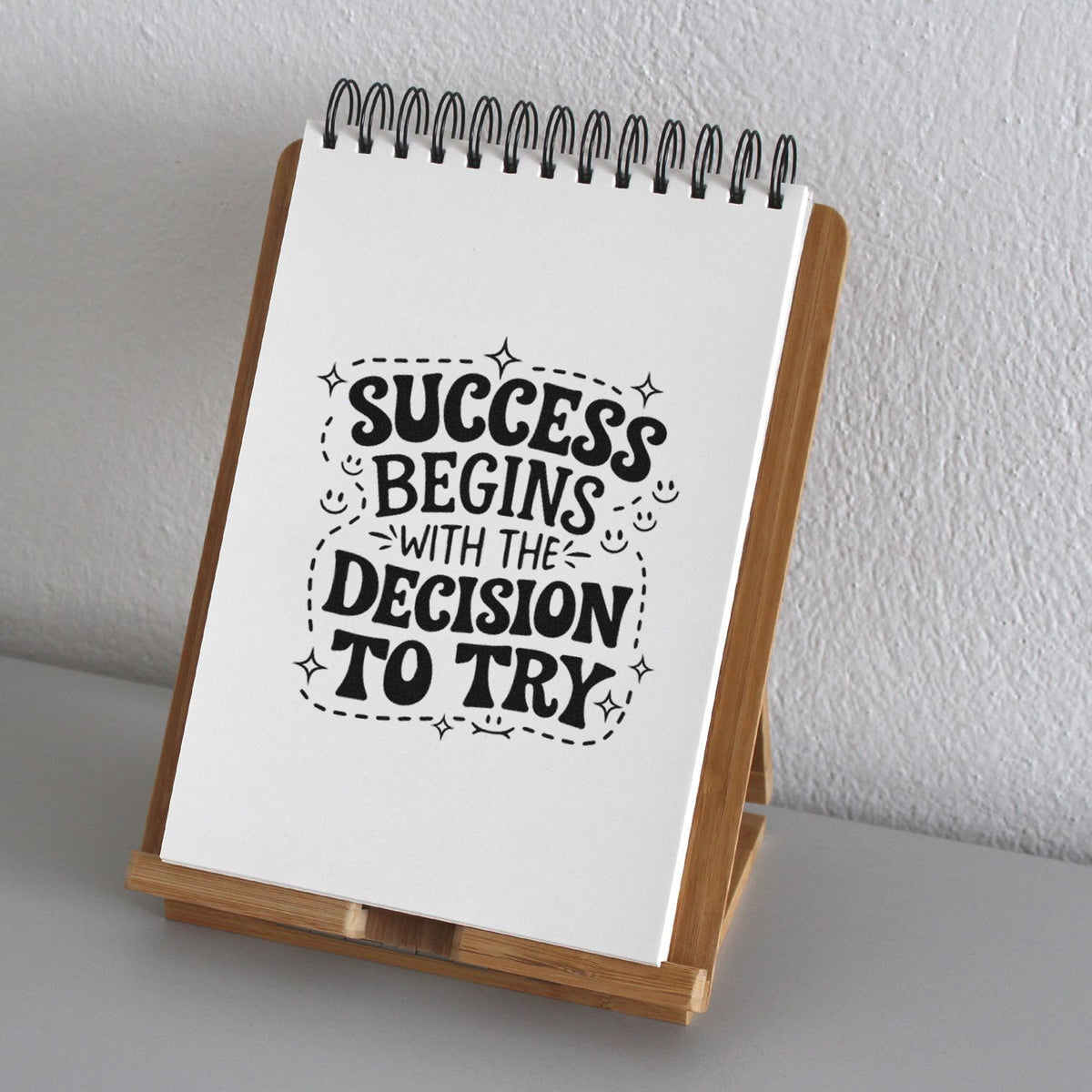 Inspirational rubber stamp quote reading Success begins with the decision to try displayed on a spiral notebook.