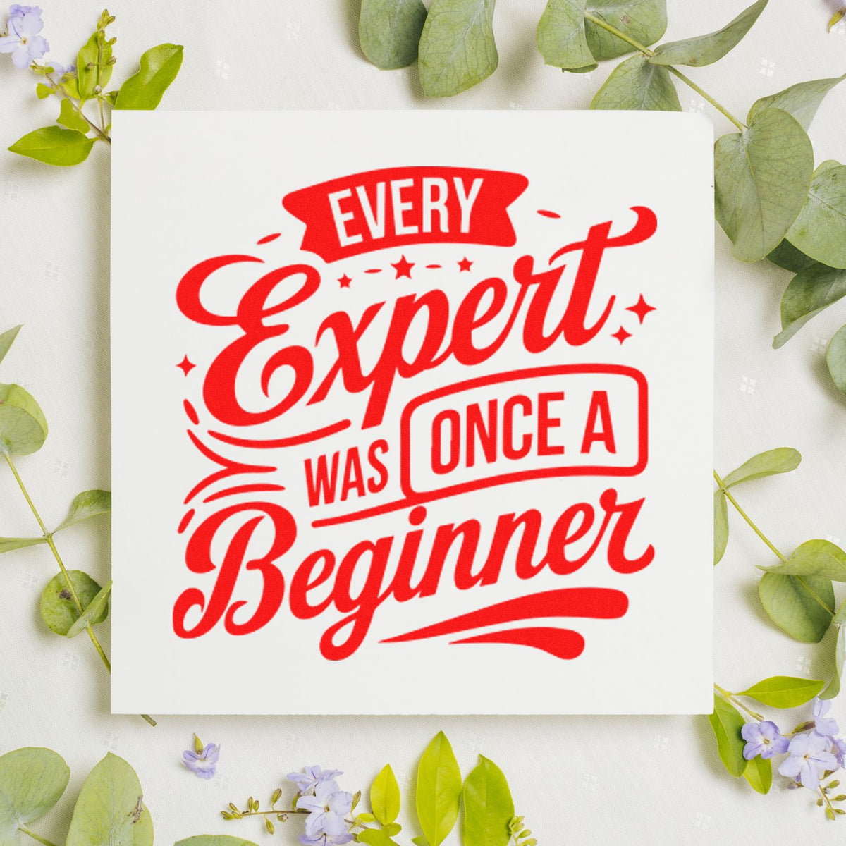 Inspirational rubber stamp design reading Every Expert Was Once a Beginner in bold red on a floral background
