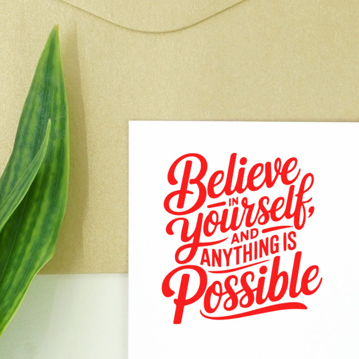 Inspirational rubber stamp quote reading Believe in yourself, and anything is possible in bold red on white paper.