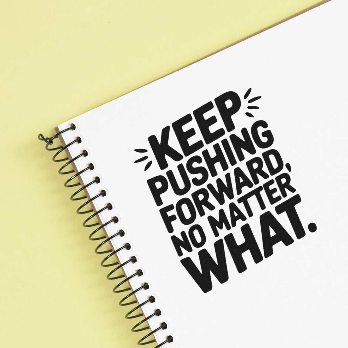 Motivational rubber stamp design on spiral notebook reading Keep pushing forward, no matter what.