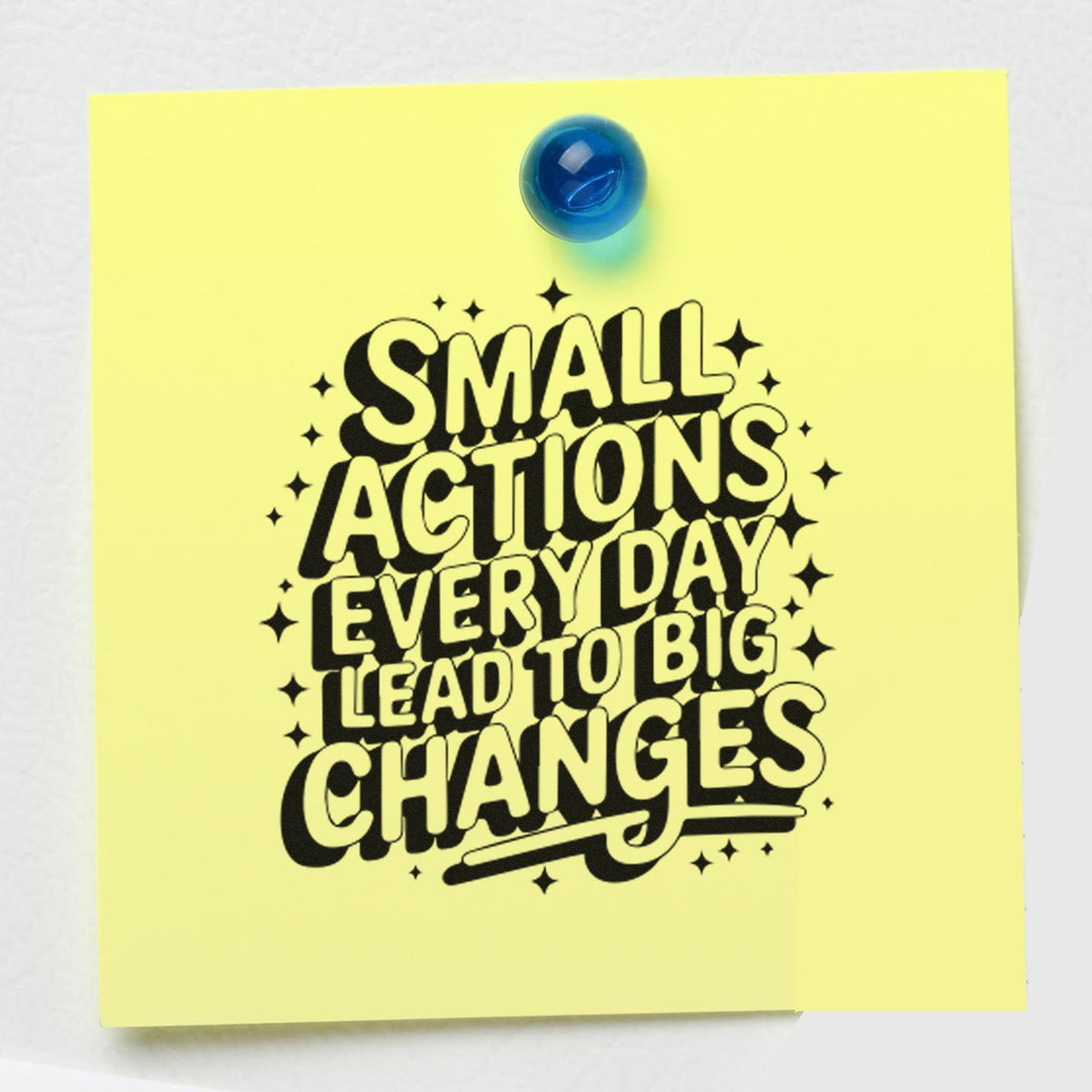 Rubber stamp quote design reading Small actions every day lead to big changes on a yellow note, pinned with a blue tack.