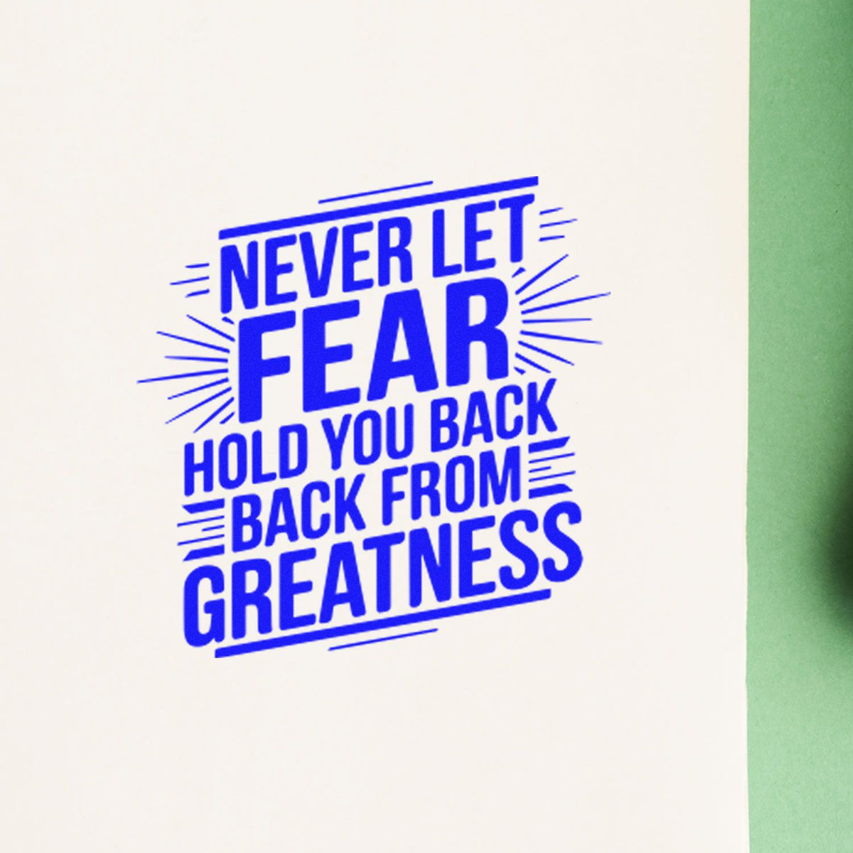 Motivational rubber stamp message: Never let fear hold you back from greatness in blue ink on paper.