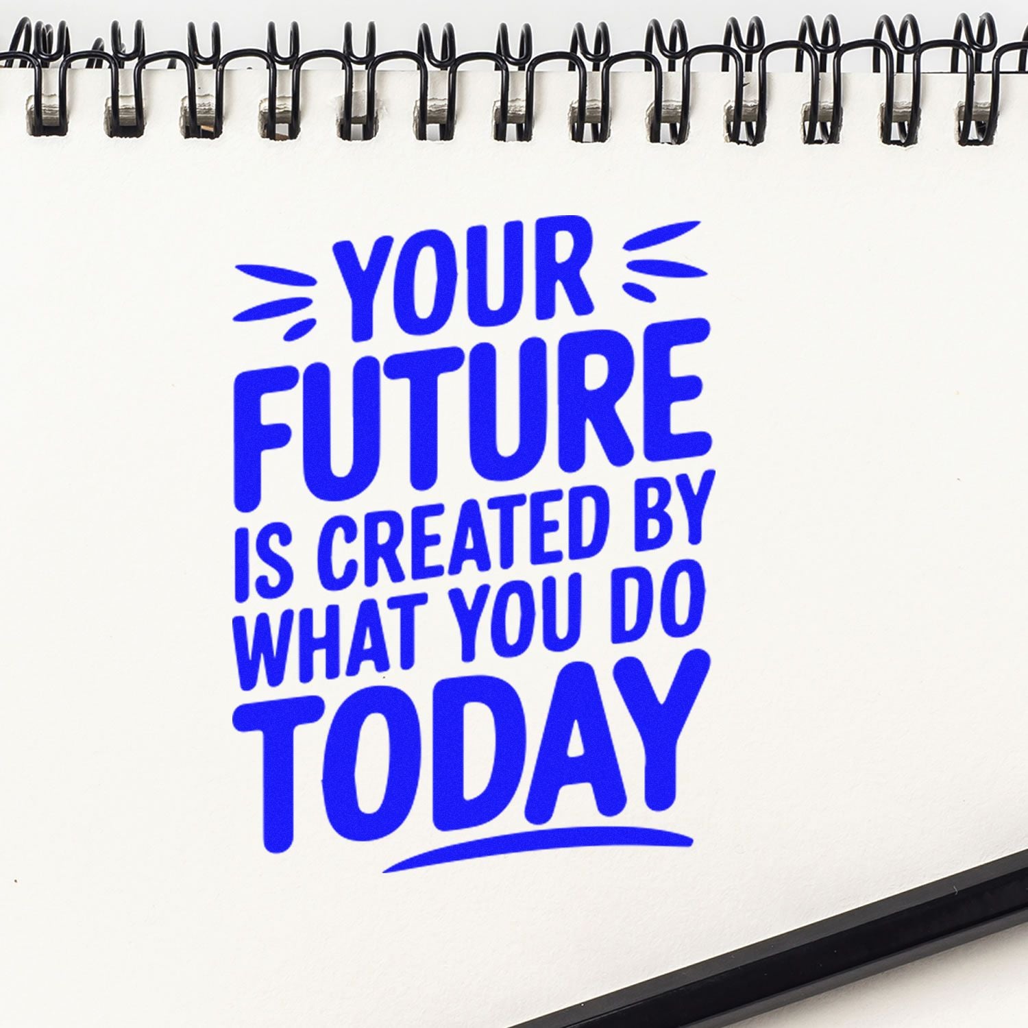 Motivational rubber stamp design with blue quote, Your future is created by what you do today, on a spiral notebook page.