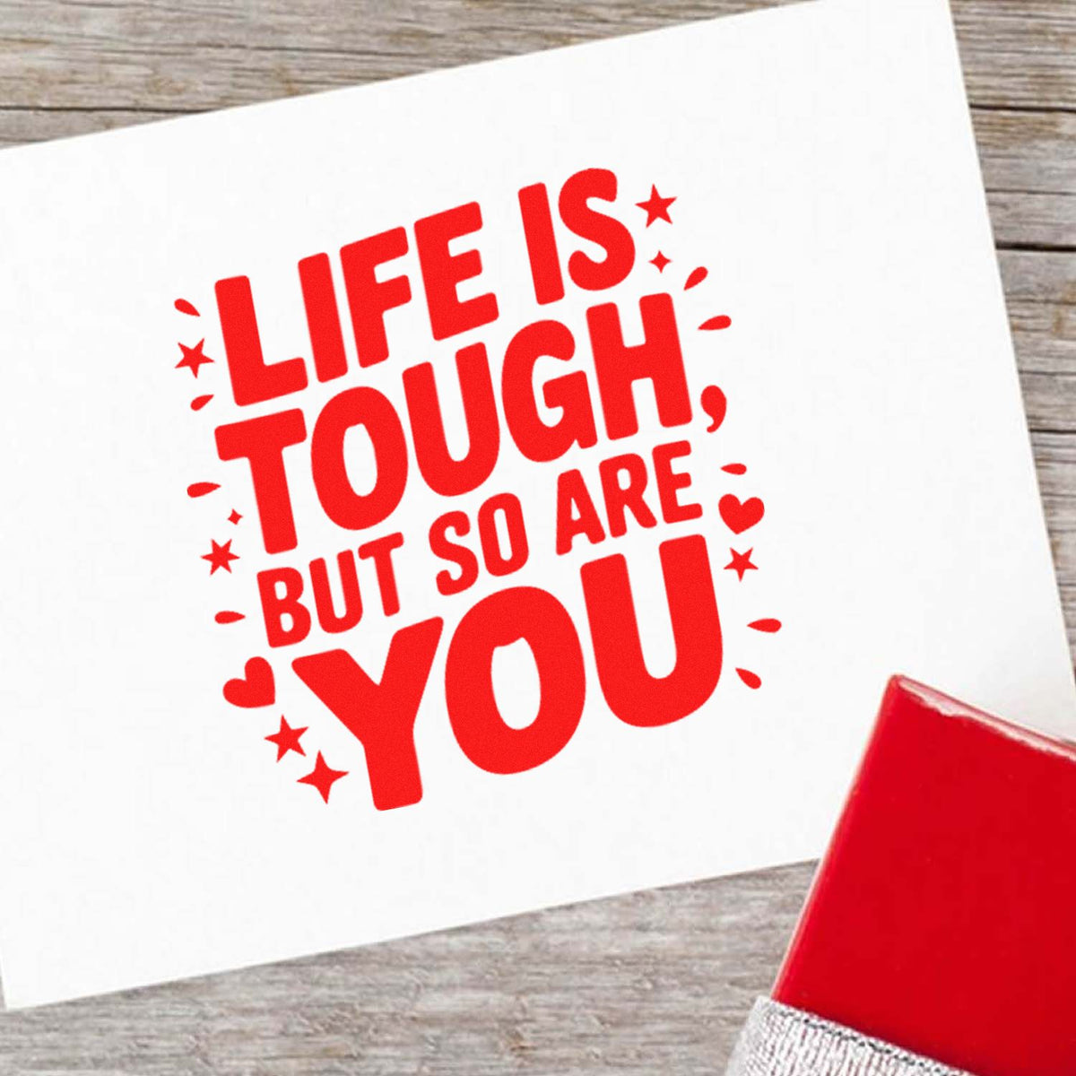 Inspirational rubber stamp design reading Life is tough but so are you in red with stamp pad on white card.