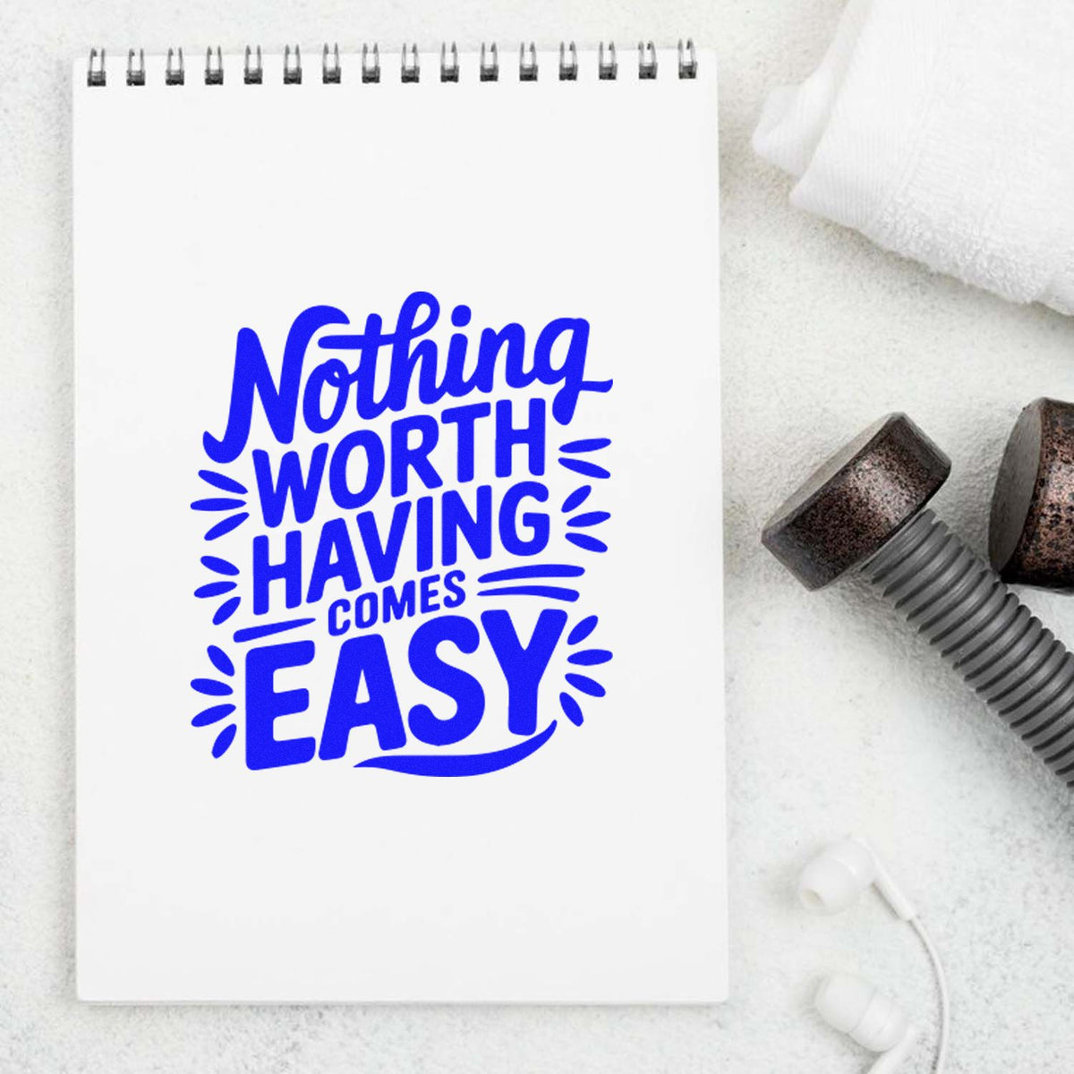 Custom rubber stamp quote design reading Nothing Worth Having Comes Easy in bold blue lettering on a notebook mockup.