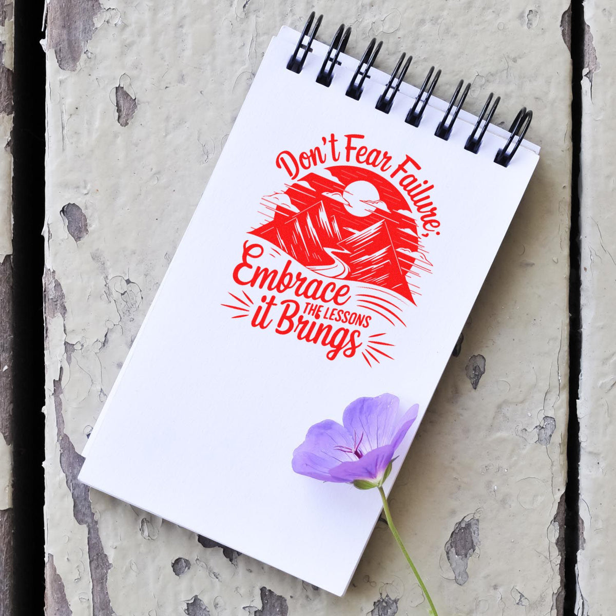 Inspirational rubber stamp design on notebook with mountain graphic and quote about embracing failure and lessons learned.