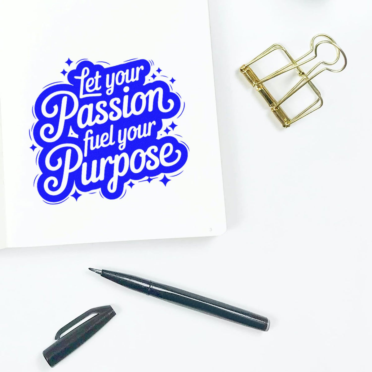 Motivational rubber stamp impression reading Let your passion fuel your purpose on paper with pen and binder clip.
