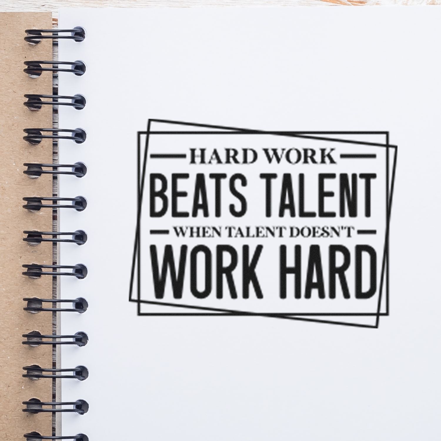 Custom rubber stamp with motivational quote: Hard work beats talent when talent doesnt work hard, stamped on notebook paper.
