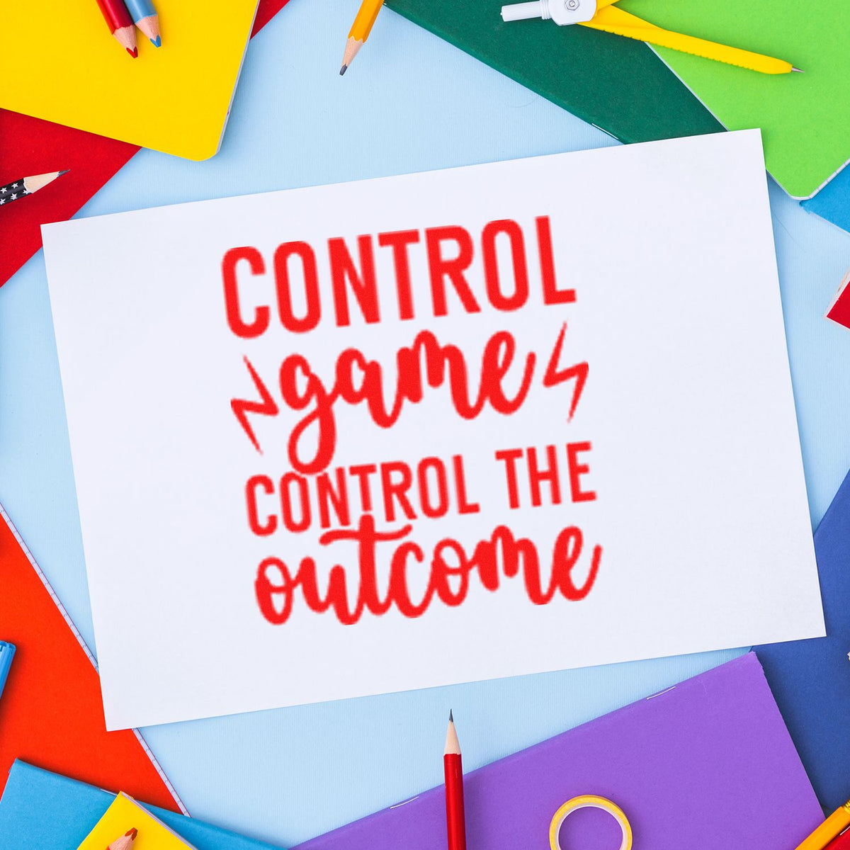 Rubber stamp design with red motivational quote, Control games, control the outcome, on paper with colorful school supplies.