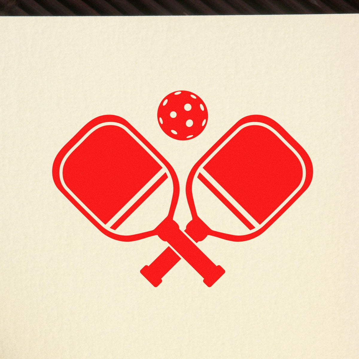Pickleball rubber stamp design featuring crossed paddles and ball in red.