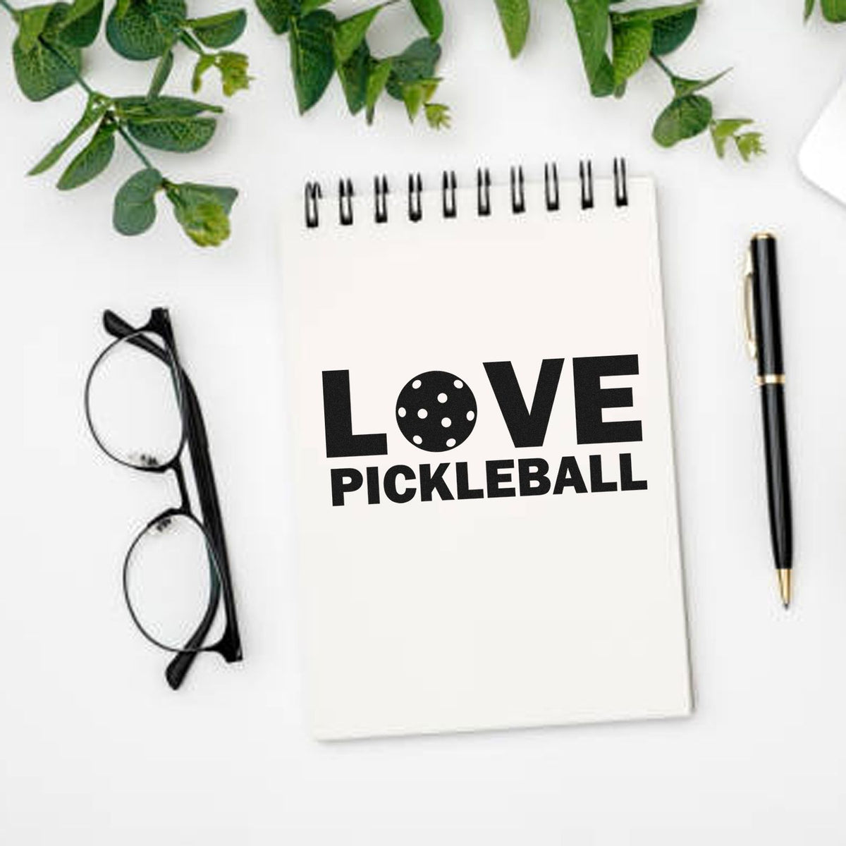 Love Pickleball rubber stamp design on a notebook, ideal for custom stationery and pickleball gift branding.