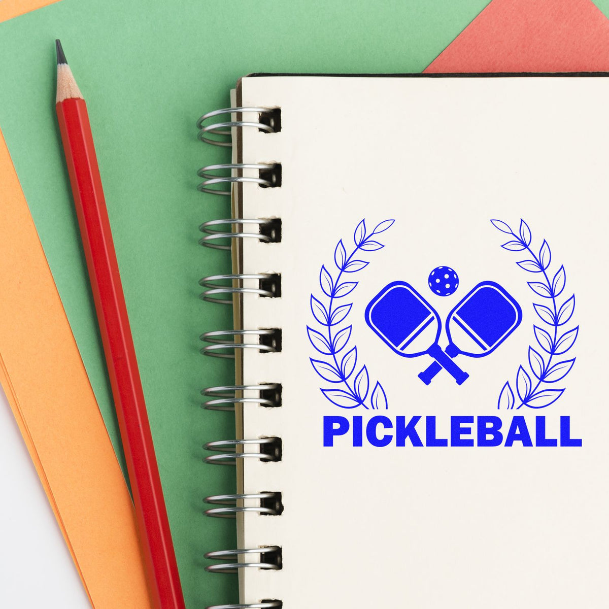 Pickleball rubber stamp design with crossed paddles on a notebook, ideal for custom sports stamping and craft projects.