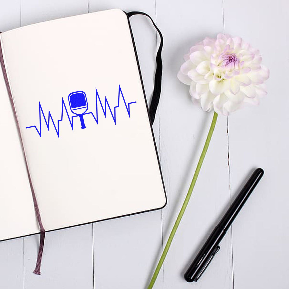Custom rubber stamp logo with blue heartbeat microphone design on notebook, ideal for personalized branding and stationery.