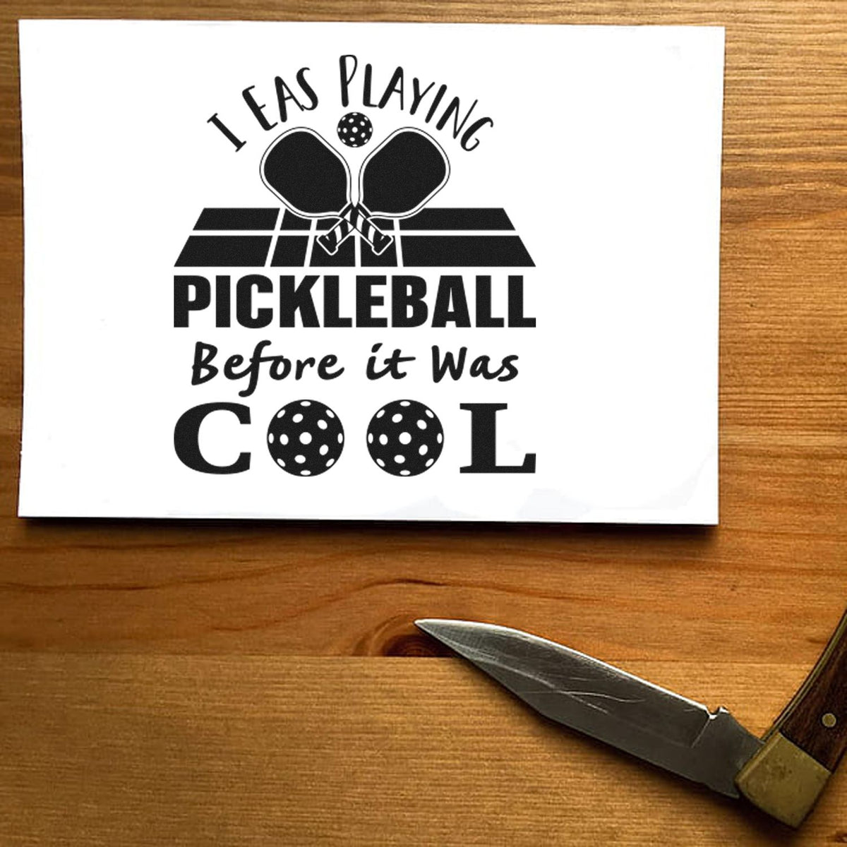 Pickleball Before It Cool PSI Pre-Inked Stamp imprint stamped in blue ink. I WAS PLAYING PICKLEBALL Before it Was COOL appears with crossed paddles, a court, and perforated ball letters.
