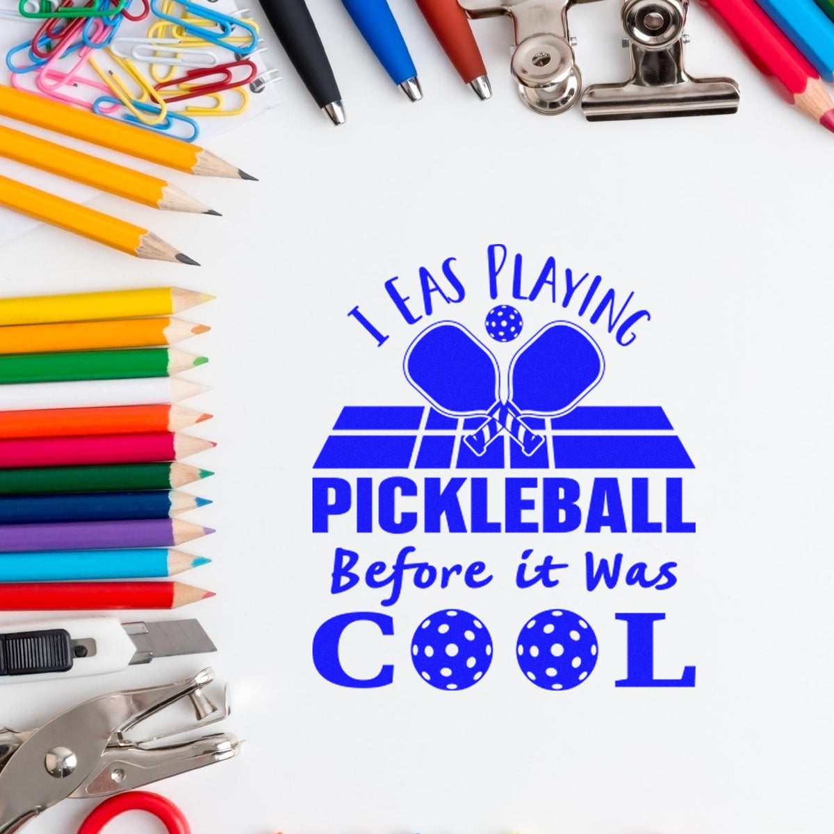 Custom rubber stamp design with pickleball quote, surrounded by pencils and office supplies.