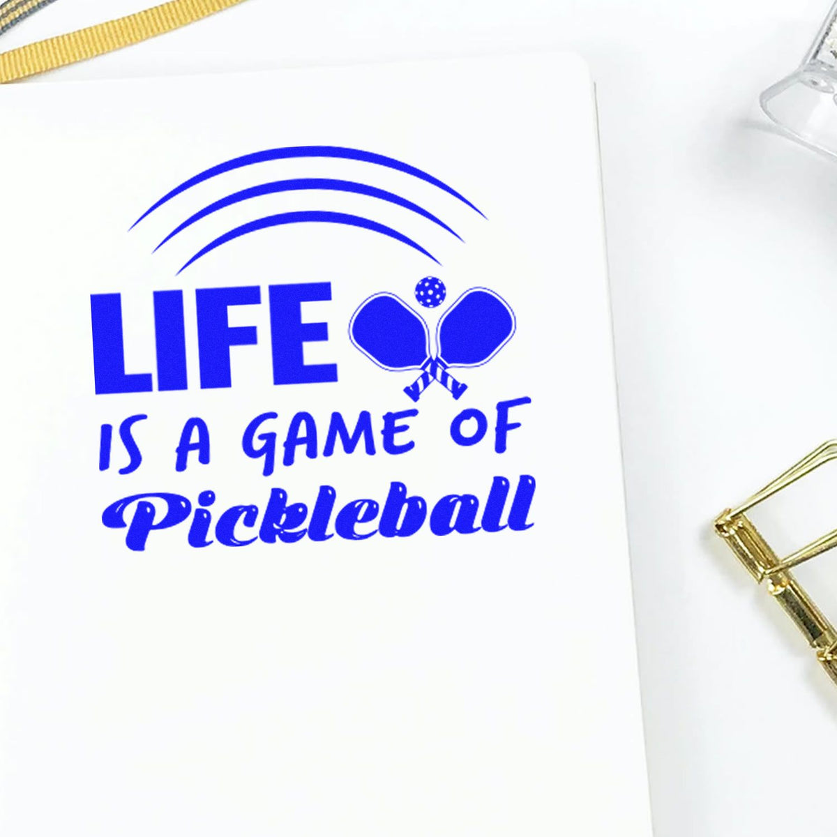 Blue pickleball rubber stamp impression with Life is a game of pickleball quote for sports-themed stationery