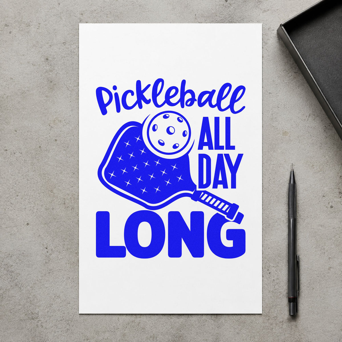Pickleball All Day Long craft stamp imprinted in blue ink on paper, a design suited to framed sign in table.
