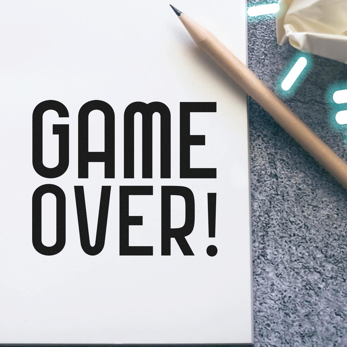 Bold Game Over rubber stamp-style text on a notebook page with pencil, perfect for custom stamps and craft branding.