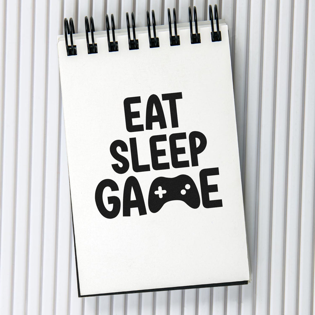 Eat Sleep Game rubber stamp design with bold black lettering and video game controller icon.