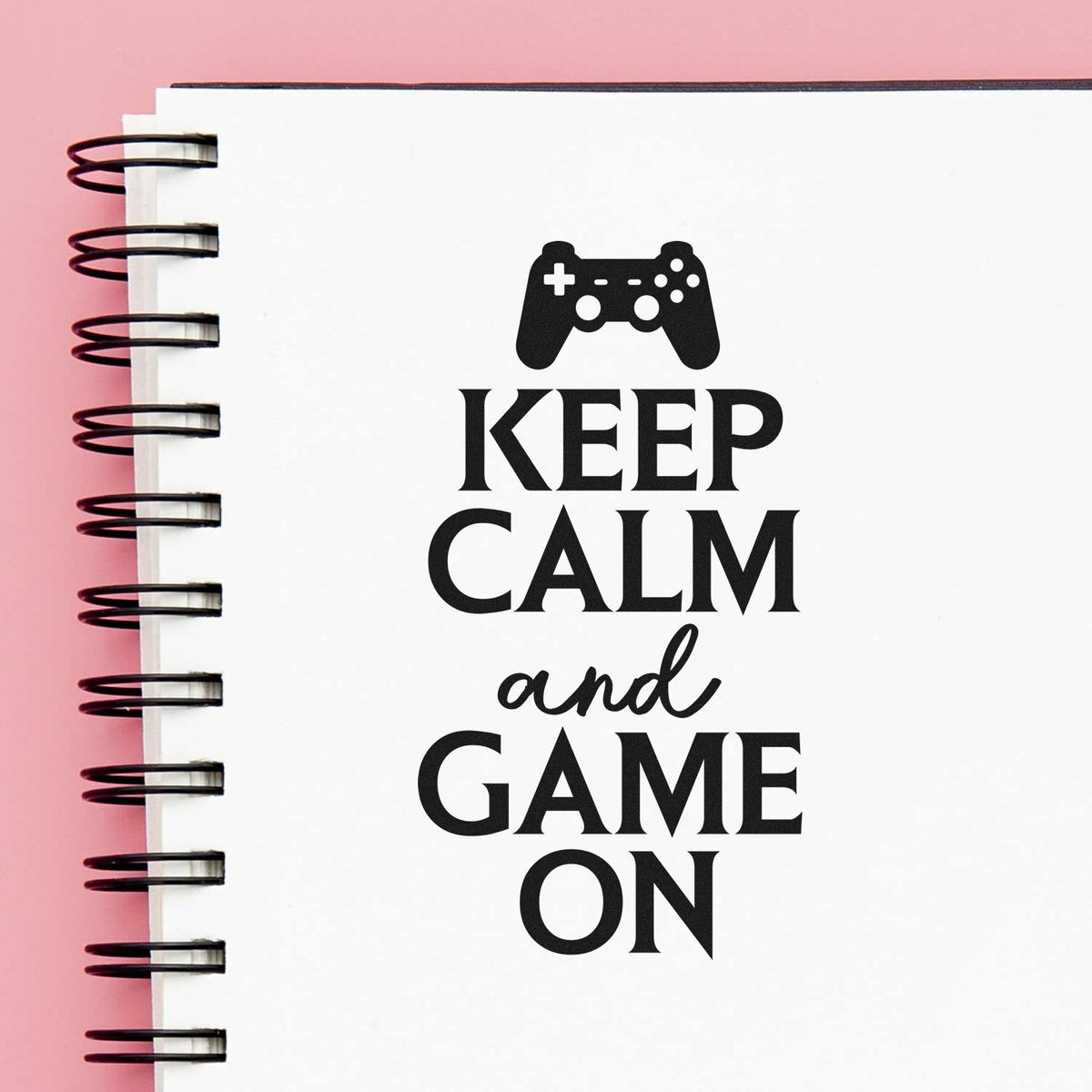 Gaming-themed rubber stamp design reading Keep Calm and Game On with controller icon on notebook page.