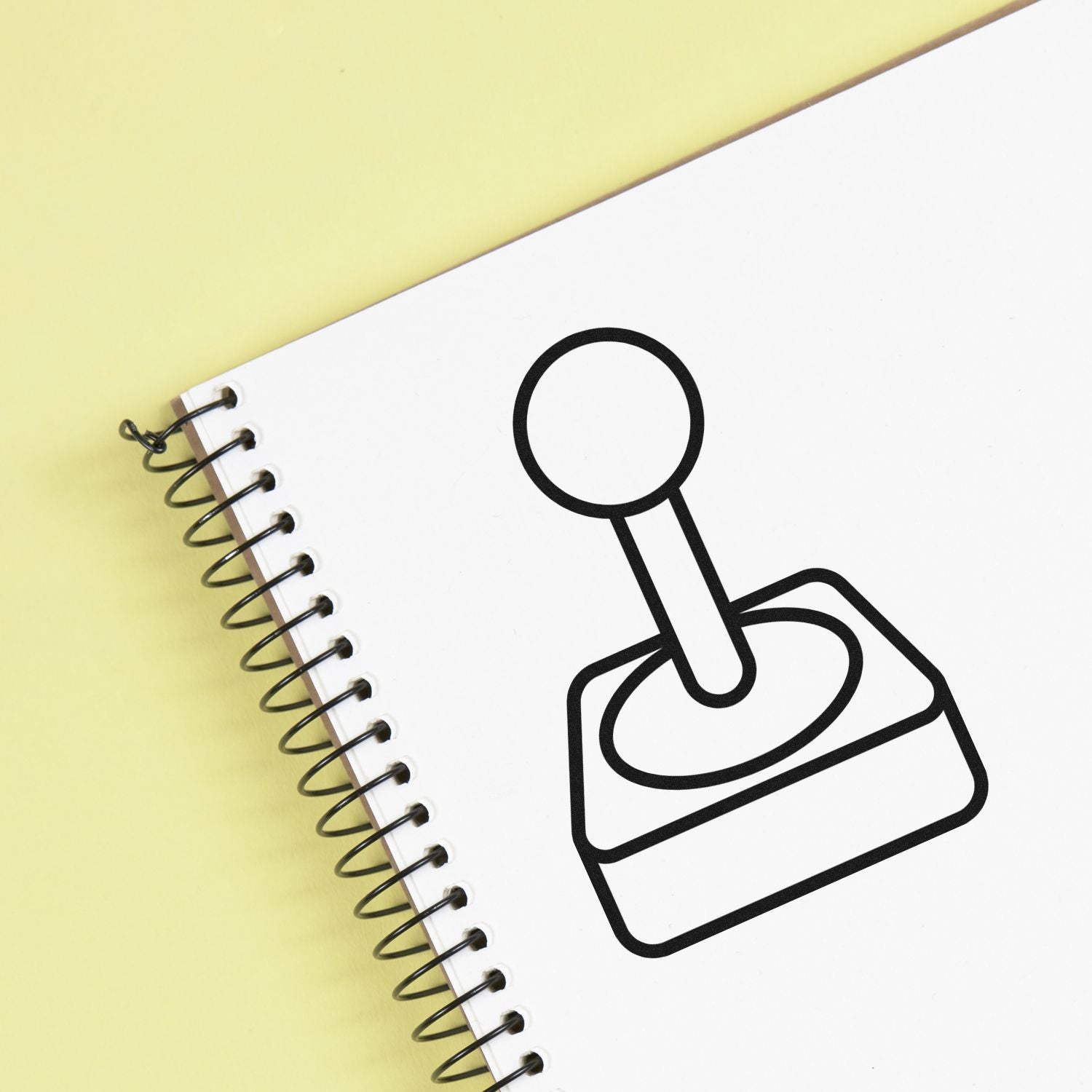 Rubber stamp icon on spiral notebook page, showing custom stamp design for business branding and office use.