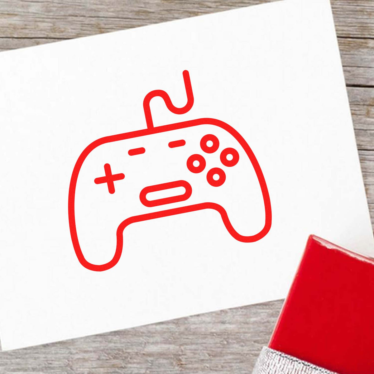 Red game controller rubber stamp imprint on paper for gaming-themed craft and business branding.