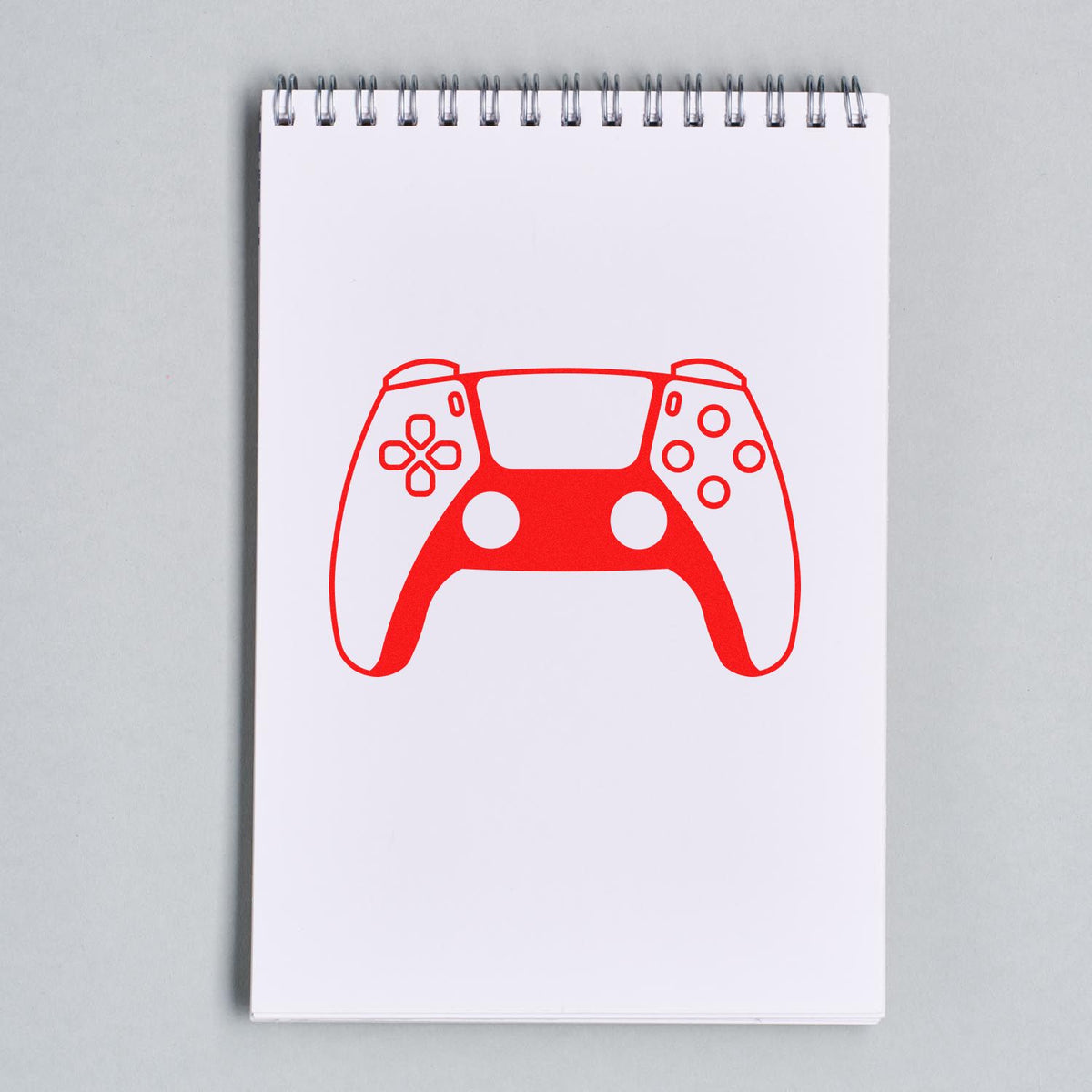 Custom video game controller rubber stamp impression on a spiral notebook page.