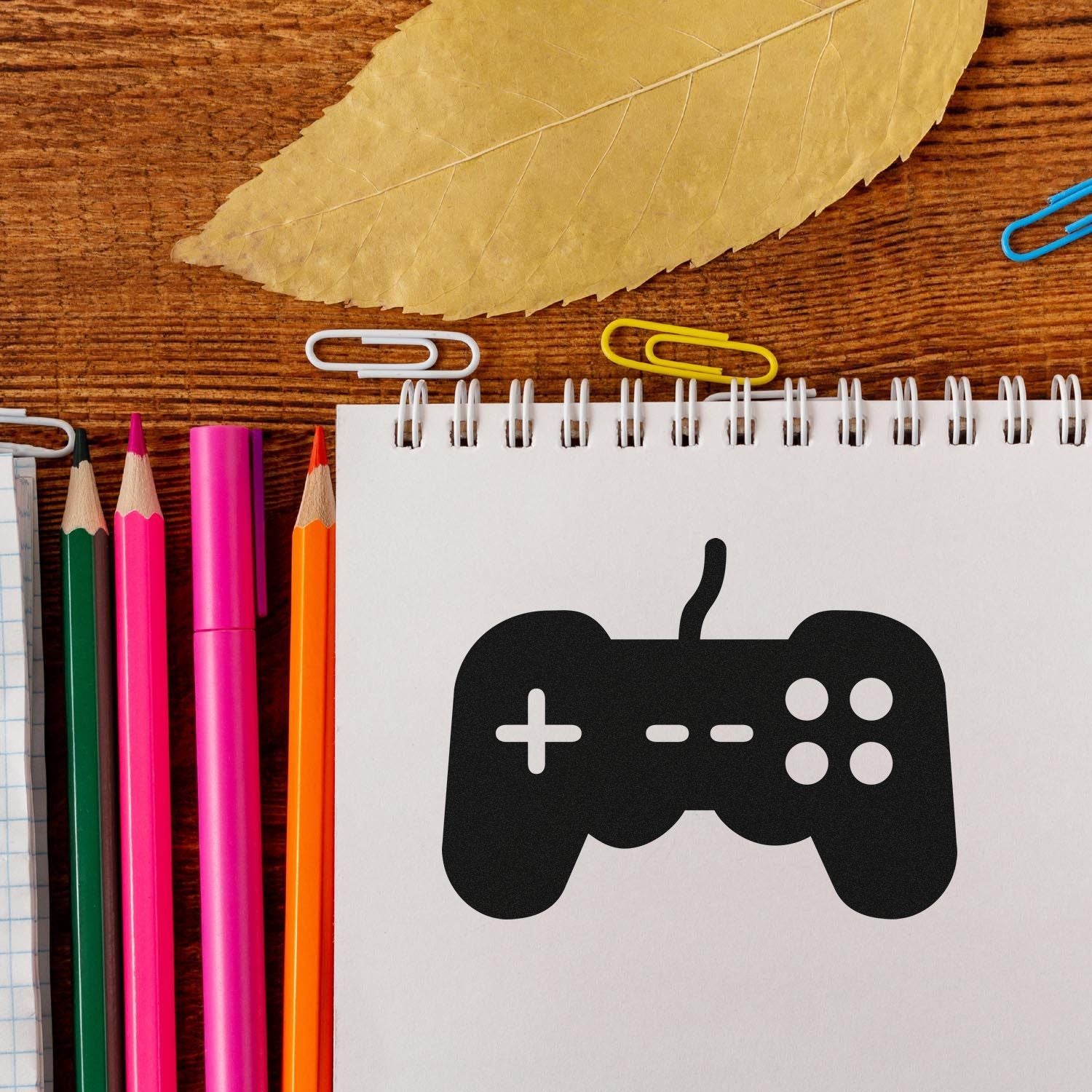 Video game controller rubber stamp on notebook page, ideal for gaming-themed stationery, planners, and craft projects.