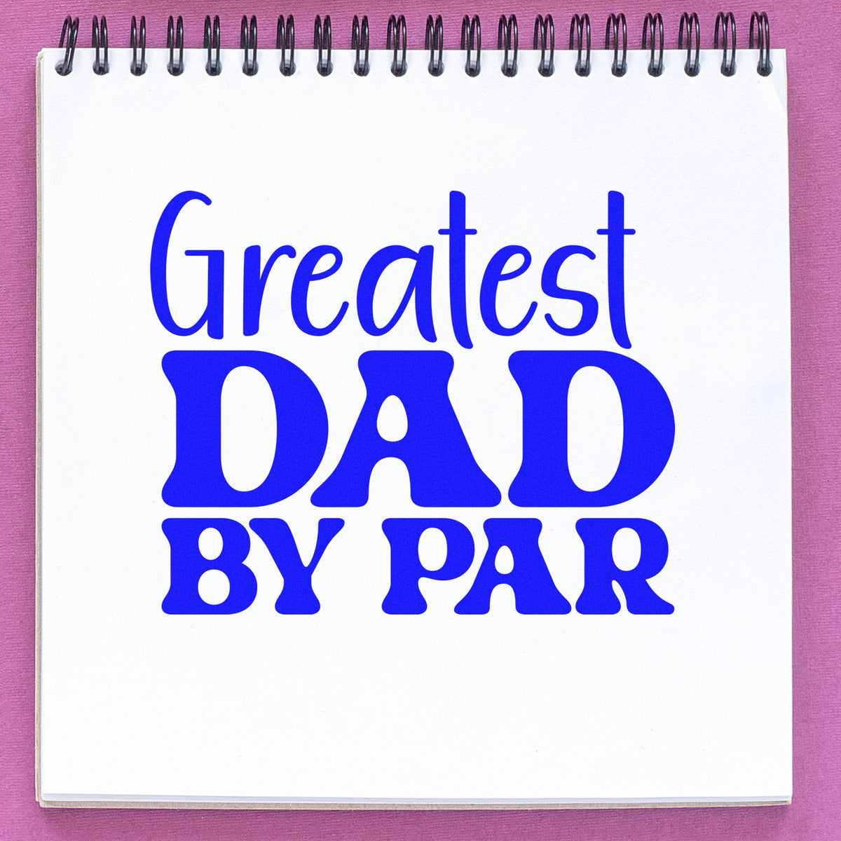 Greatest Dad by Far rubber stamp design in bold blue retro lettering on a notebook page