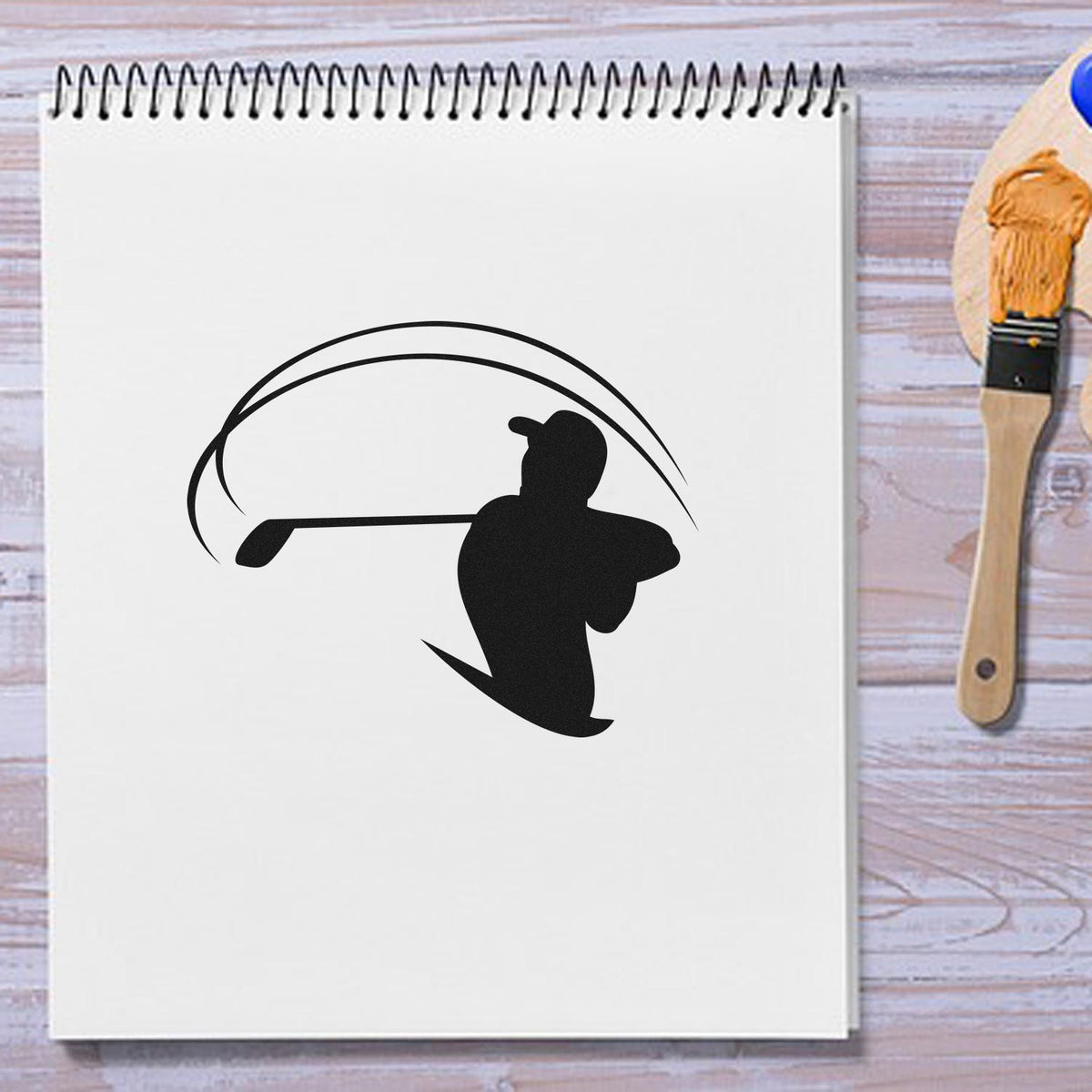Golf swing rubber stamp design on notebook, shown with a brush tool for custom sports stamping and craft projects.