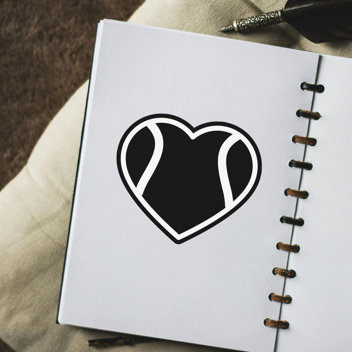 Heart-shaped custom rubber stamp logo printed on a notebook page for branding or stationery design.