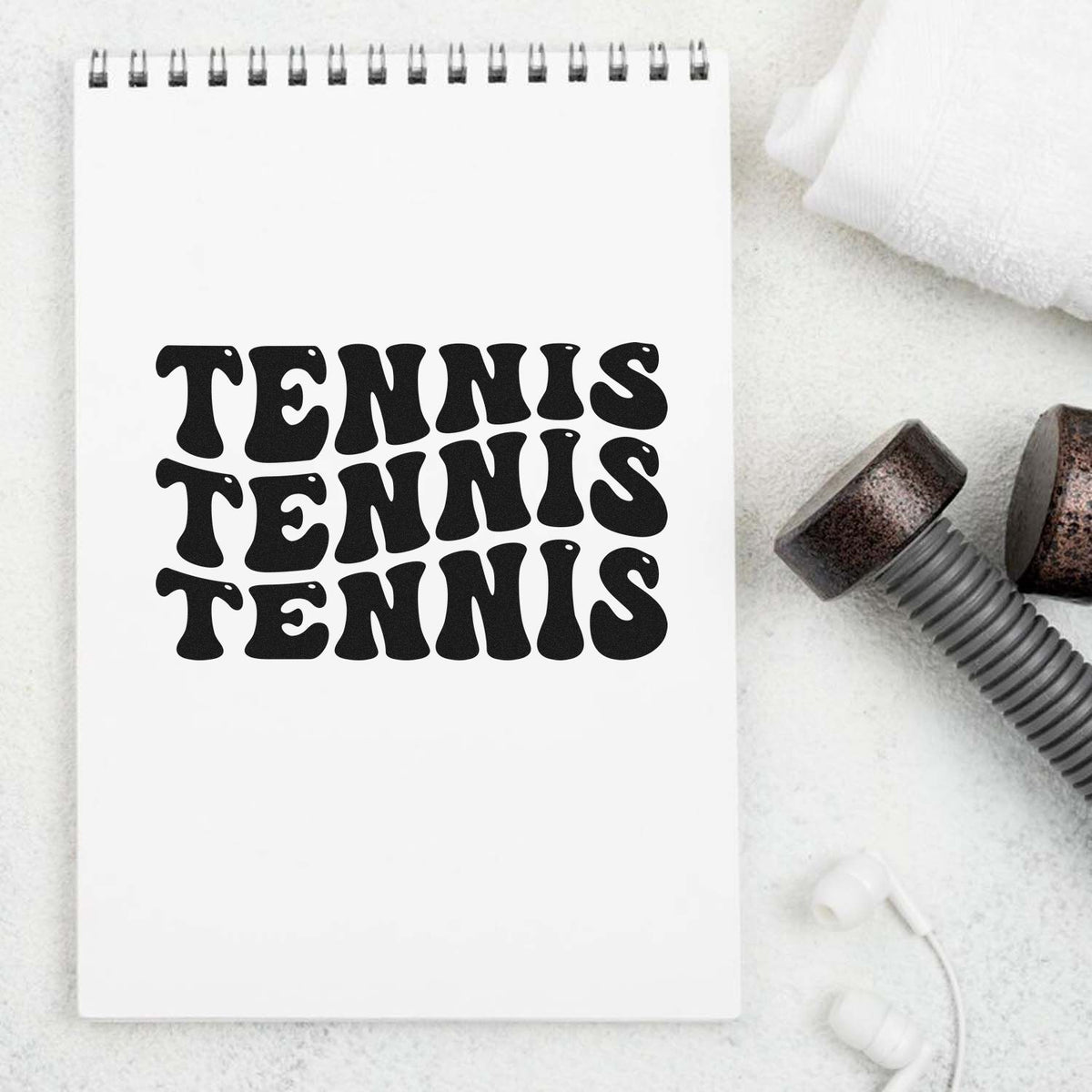 Tennis rubber stamp design with bold retro lettering on notebook, shown with stamp tools for custom sports crafts.