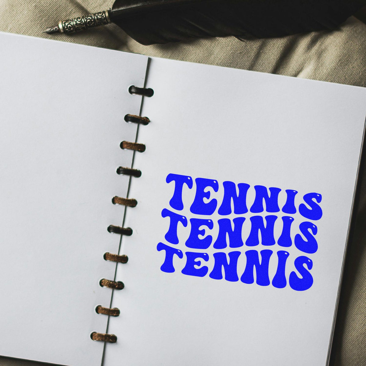 Blue tennis rubber stamp impression on a notebook page, ideal for sports branding, crafts, or custom stationery.