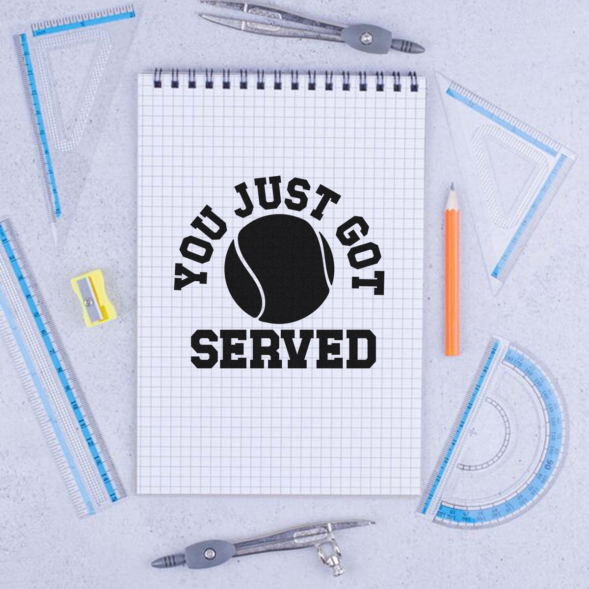Custom tennis rubber stamp design with You Just Got Served and tennis ball graphic on a notebook.