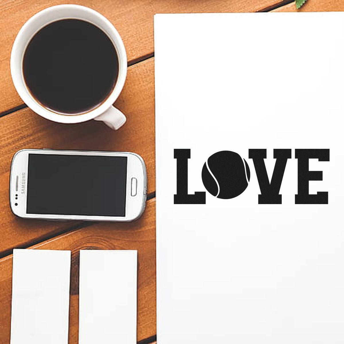 Custom rubber stamp design with LOVE on paper beside coffee, smartphone, and blank cards on a wooden desk.