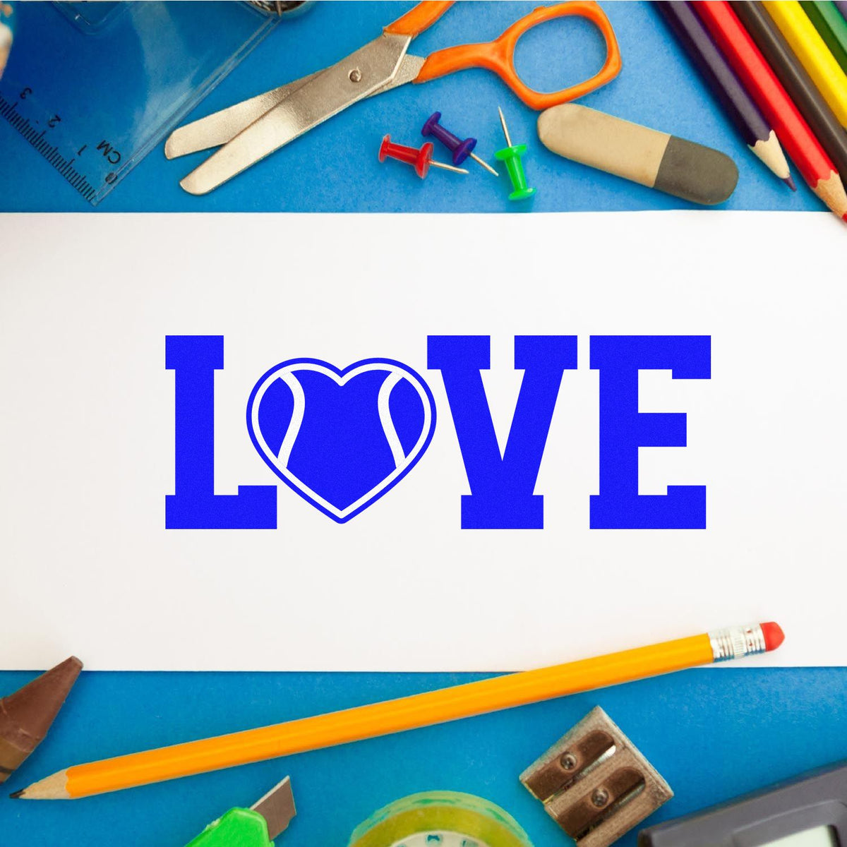 Blue LOVE rubber stamp design with heart icon, framed by school supplies on a blue craft background.