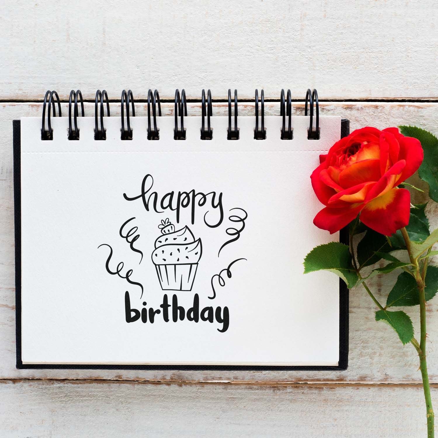 Happy birthday cupcake rubber stamp design on notebook, perfect for handmade birthday cards and craft projects with a festive floral touch