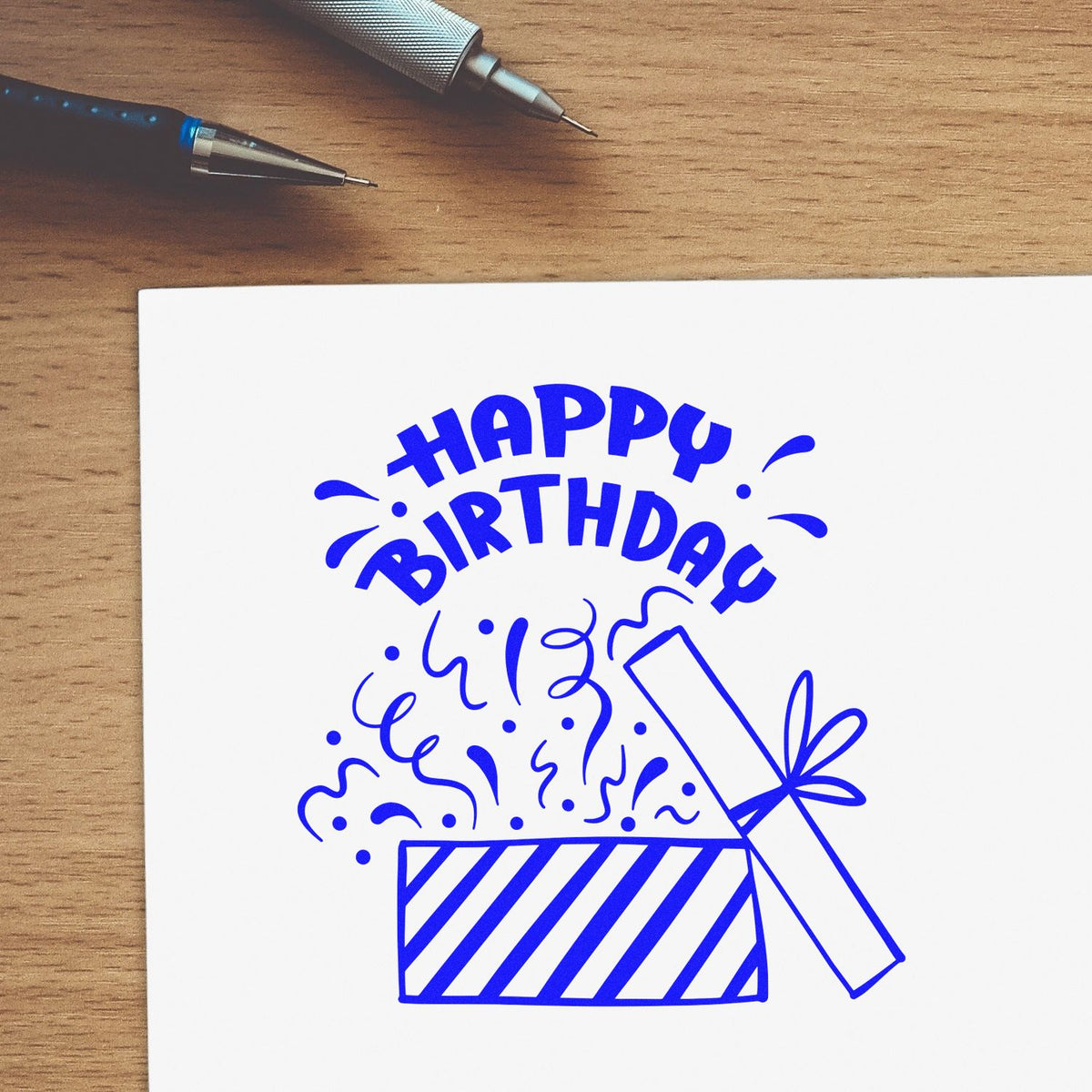 Birthday Open Gift Confetti rubber stamp shown in blue ink, stamped for projects such as wrapping album page.