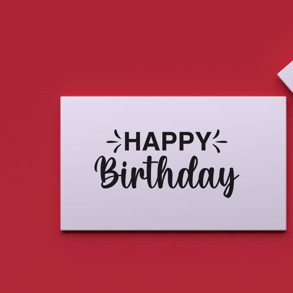Happy Birthday rubber stamp design with bold black lettering on a white card against a red background.