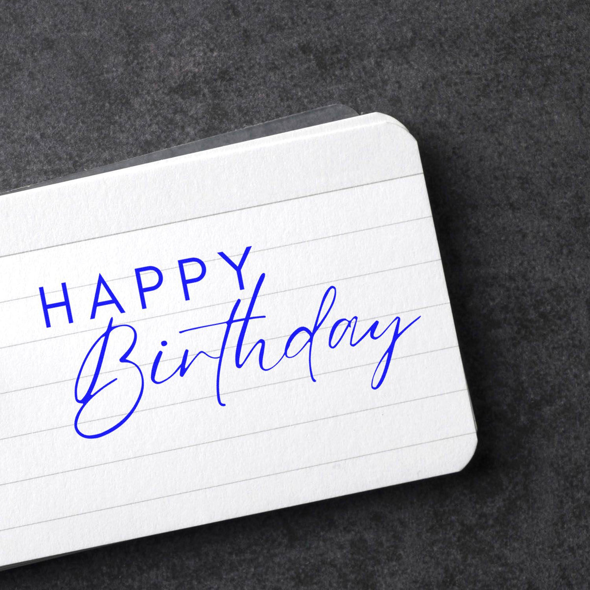 Happy Birthday rubber stamp impression on lined paper for birthday cards, scrapbooking, and personalized stationery.