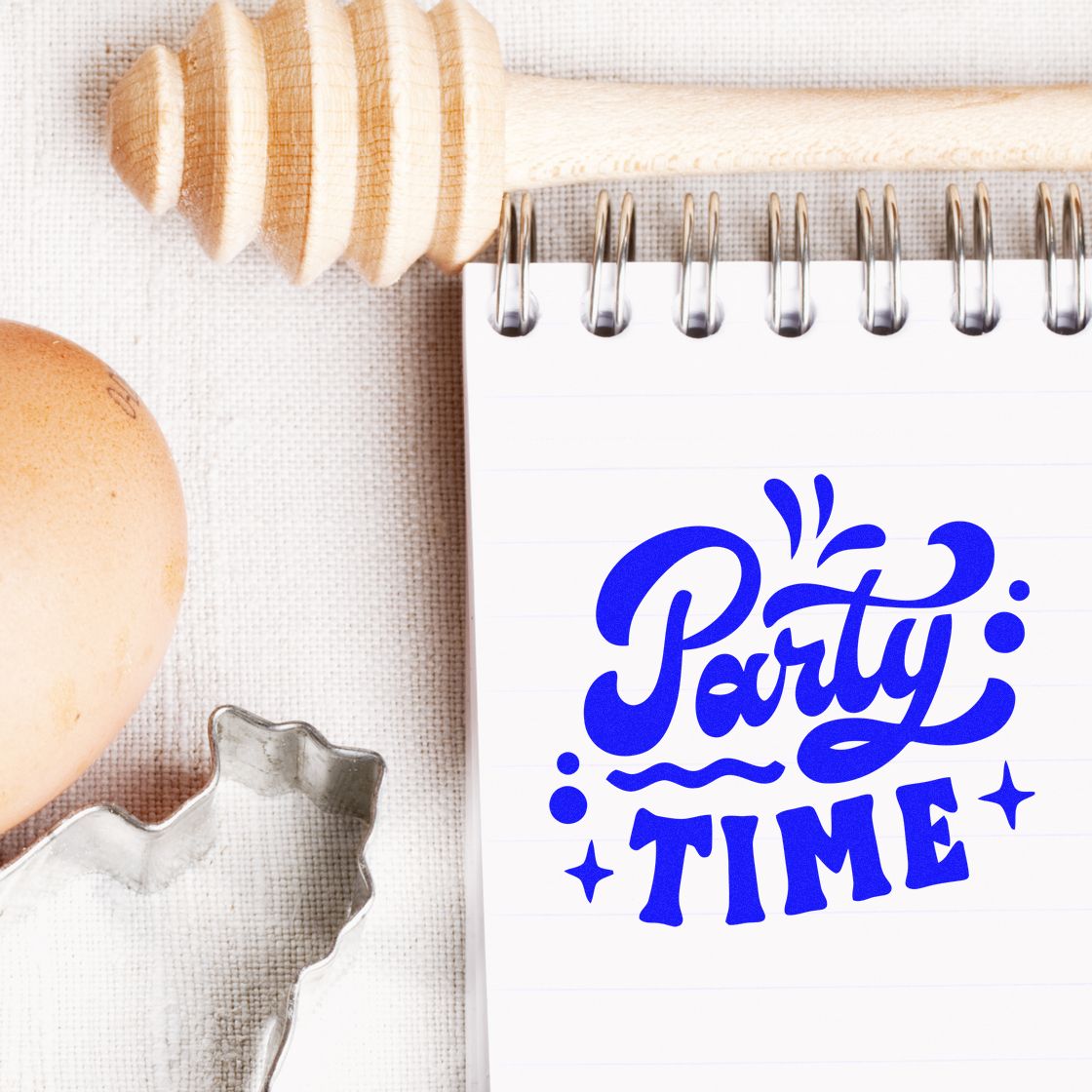 Blue Party Time rubber stamp design on notebook with wooden stamp and crafting tools for festive party projects.