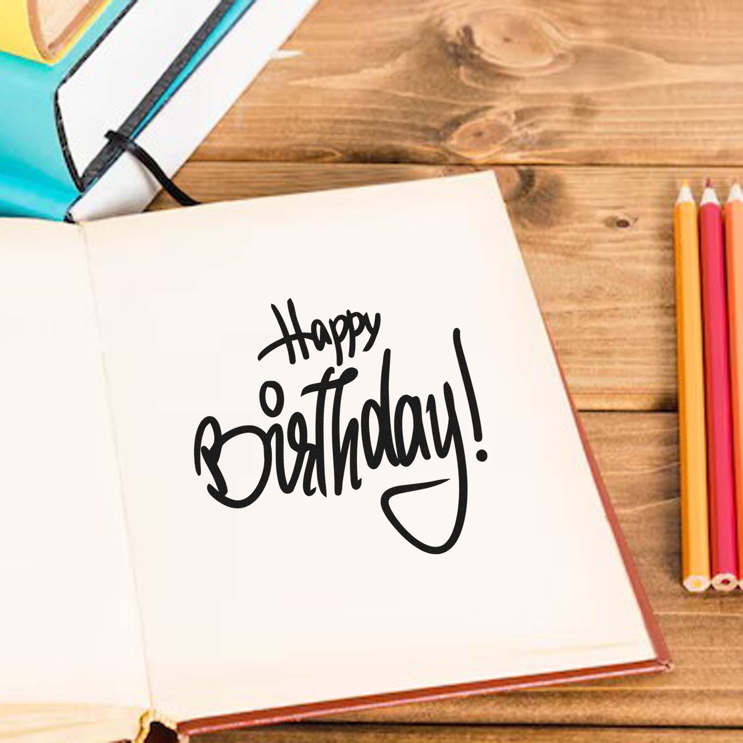 Happy Birthday rubber stamp design in script on open notebook, perfect for handmade birthday cards and craft projects.