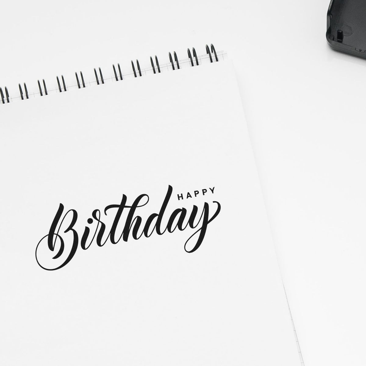 Happy Birthday rubber stamp impression on a notebook page, ideal for handmade cards, scrapbooking, and craft packaging.