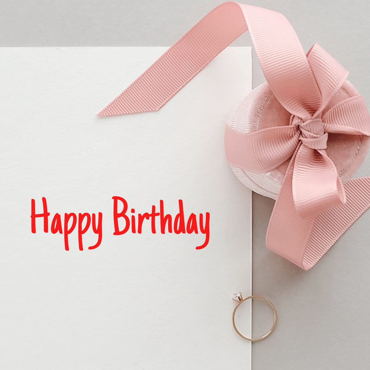 Happy Birthday rubber stamp on a white greeting card with pink ribbon bow, perfect for birthday cardmaking and gift packaging.