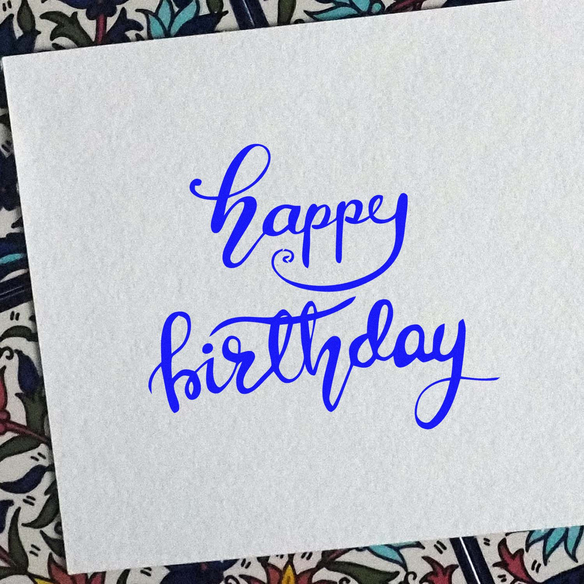 Blue happy birthday rubber stamp in elegant script on white paper for handmade cards, scrapbooking, and birthday crafts.