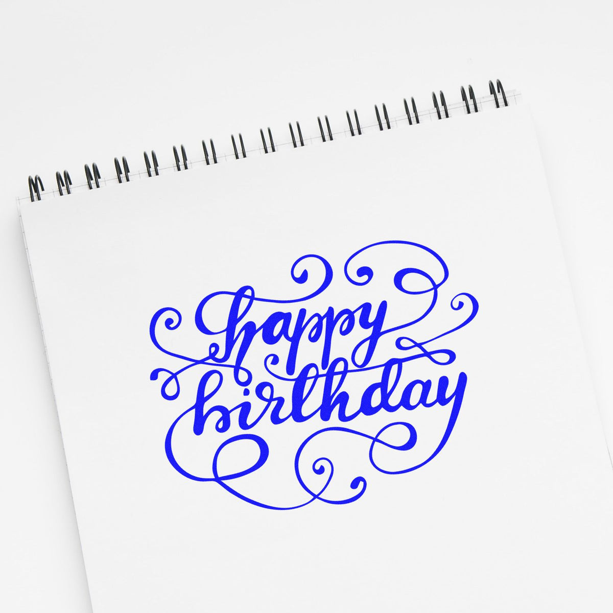 Decorative Happy Birthday rubber stamp design in blue script on a notebook page, ideal for custom birthday card stamping.