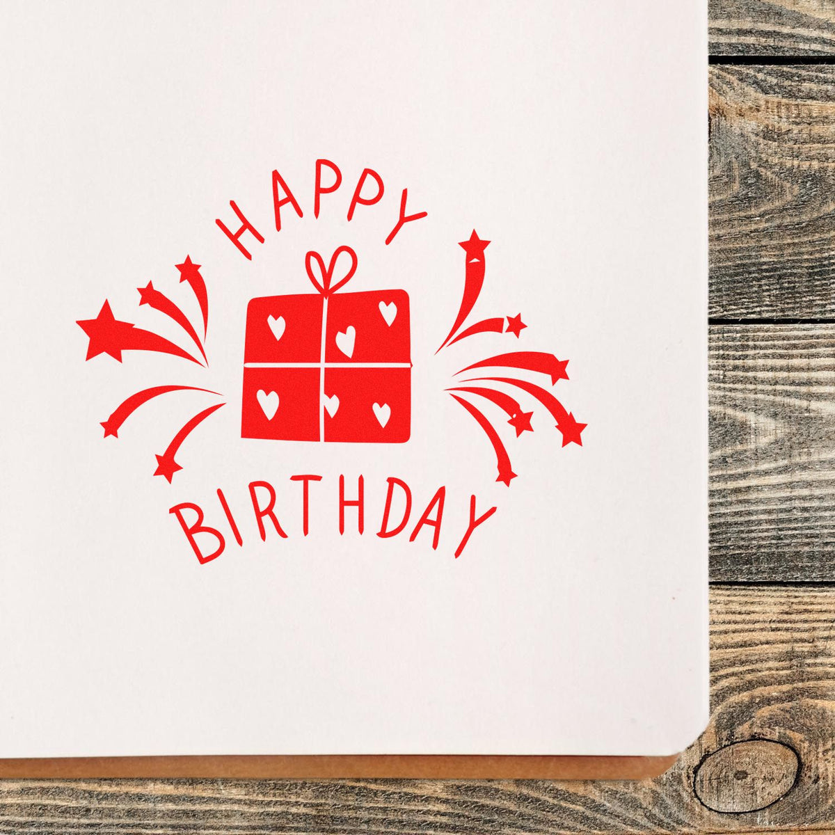Happy Birthday rubber stamp with gift and fireworks design, stamped in red on white paper for birthday card making.