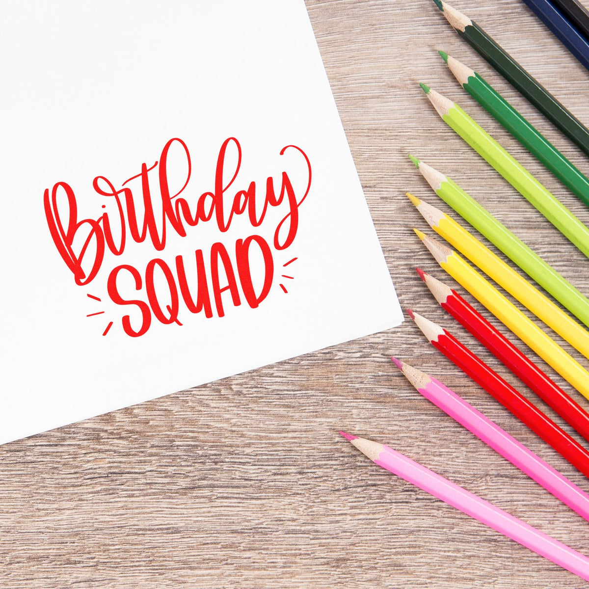 Birthday Squad rubber stamp design on white paper with colorful pencils, ideal for party invitations and craft projects.