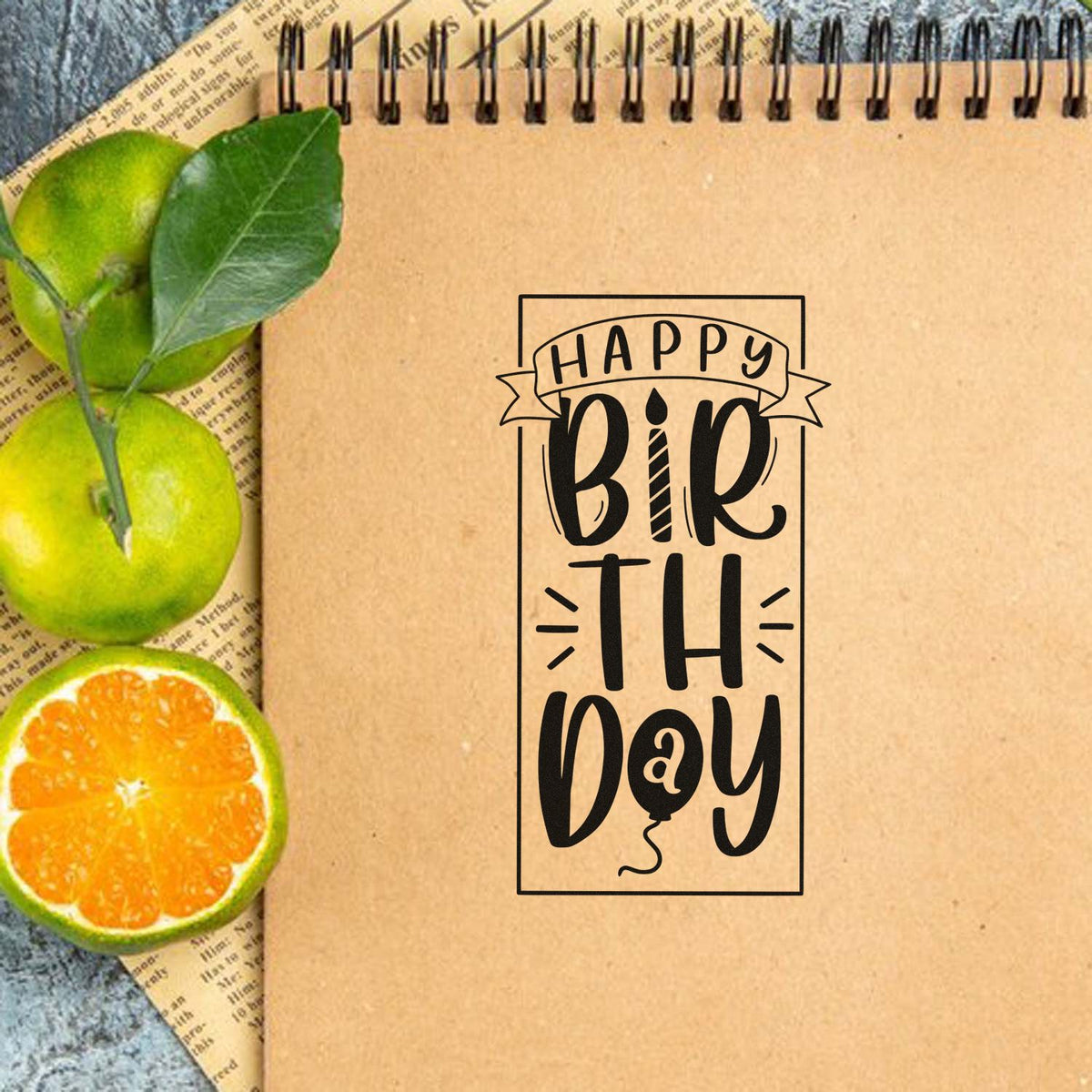 Happy Birthday rubber stamp design on kraft notebook with citrus accents, ideal for handmade cards, scrapbooking, and journaling.